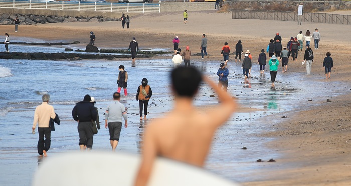 지난 주말 휴일동안 낮 기온이 20도를 훌쩍 웃도는 등 포근한 날씨를 보이면서 10일 오후 제주시 이호해수욕장을 찾은 시민들이 맨발로 해변을 걸어가고 있다. 일부 시민들은 상의를 탈의하고 서핑을 즐기기도 했다. (사진/뉴시스)